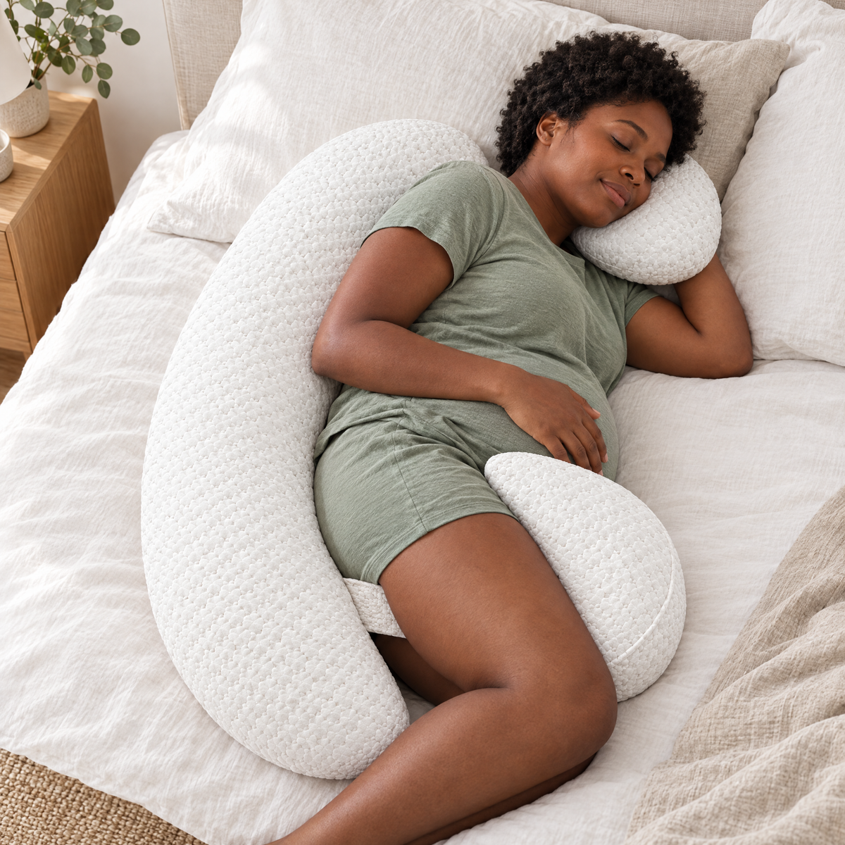 Mum-to-be resting on her side with the long pillow behind her back and the wedge under her bump